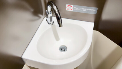 Fototapeta premium Automatic Sensor Faucet and Small Ceramic Sink in Japanese Public Restroom