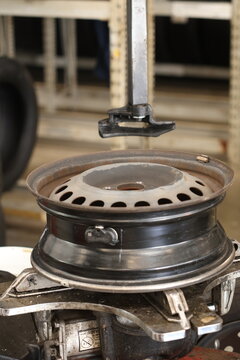 Close-up of the process on a tire-changing machine: a mechanic dismounts a car wheel (removing a tire from or mounting one onto a stamped steel rim).
