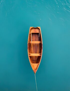 Top view of empty wooden rowboat floating on clear turquoise water minimalist style