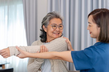 Fototapeta premium portrait asian senior woman doing rehabilitation, stretching arms by personal nurse instructing on home exercise