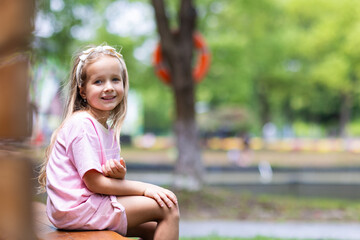 Naklejka premium Smiling Little Girl Sitting Outdoors in Park