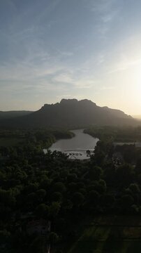 Vertical drone shot approaching Rocher de Roquebrune mountain and river, sunset
