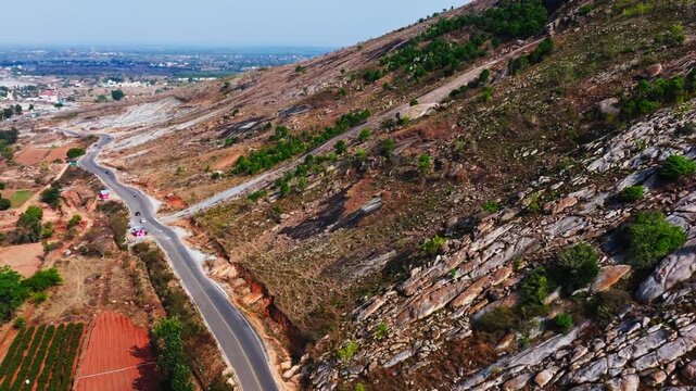 Narrow Road with mountain, farming land and plantation plants at isha adiyogi road, Avalagurki, Sonennahalli, Chikkaballapura, karnataka, india. day time, zib shot, drone shot, 4k.