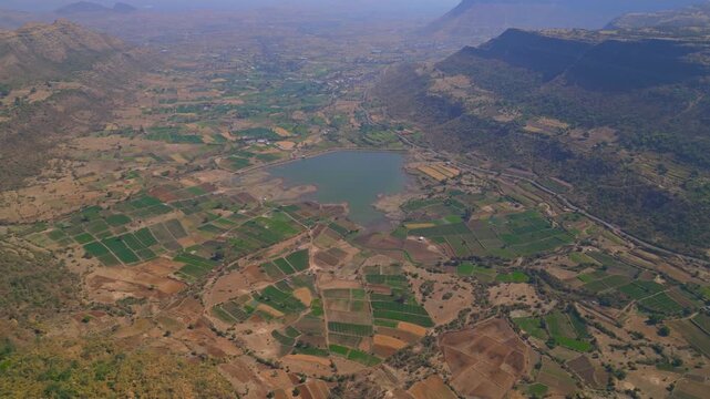 Drone footage capturing an aerial view of Pimpri Markand village farmland reservoir and surrounding valleys as seen from the Saptashrungi hill range near Vani in Nashik Maharashtra India.