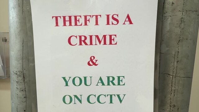 A clear security warning sign displays the message Theft Is A Crime and You Are On CCTV in red and green text on a white background. This sign serves as a deterrent against shoplifting and other