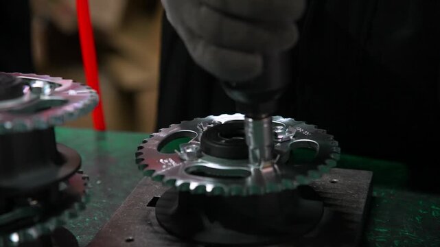 Close-up View Worker Hand Tightening Bolt with Electronic Screwdriver on Engine. Factory Assembly Line Focuses on Precise Detail Manufacturing. Professional Tool Insures High Quality Chinese Work 4k