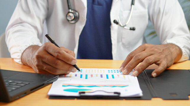 Healthcare professional analyzing medical data and patient reports with charts and graphs. Medical research, healthcare analytics, hospital management, clinical assessment, and data-driven decisions.