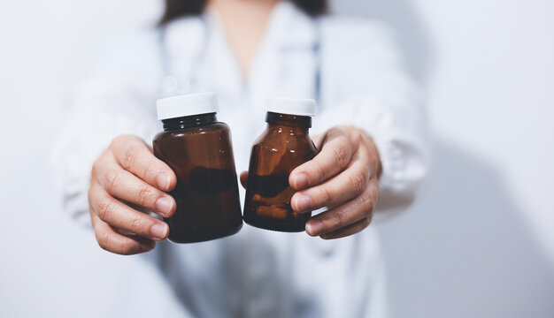 The pharmacist or doctor holding medication or medicine for treatment. Anti biotic pill in the vial.