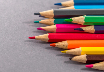 Obraz premium Colorful wooden pencils row on a grey paper background