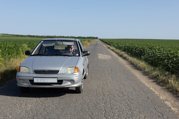 Fototapeta premium man driving car on a road between farmlands