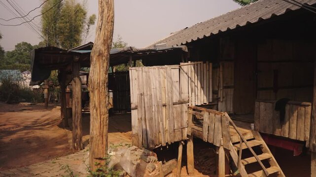 A traditional wooden house stands beside a dirt road in a rural village. This rustic countryside scene highlights local architecture, simple living, and community life.