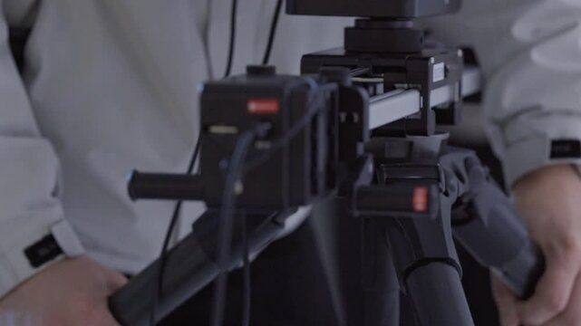 Close up of Videographer Hands Moving and Adjusting Camera Slider Tripod in Studio