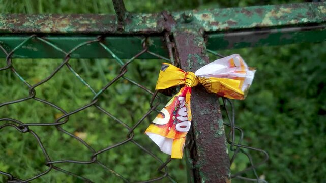 Colorful plastic wrapper tied like a bow on a rusty wire mesh fence