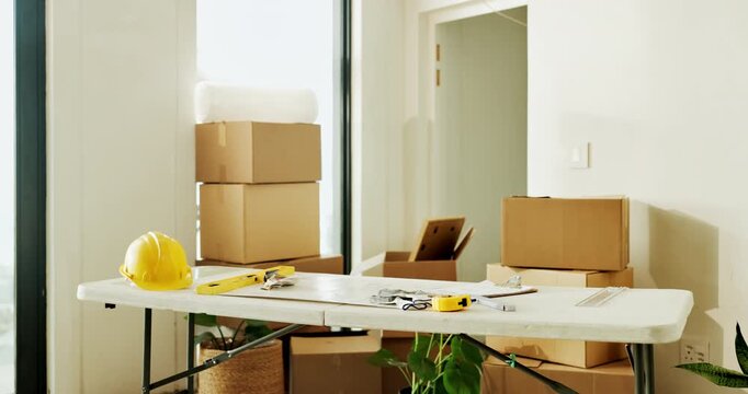 Boxes, diy and tools on table in home for improvement, maintenance or renovation project. Hard hat, level and measuring tape in room interior for construction, property development or real estate