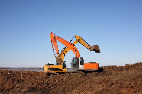 Construction - Two Excavators with crossed buckets work in dirt