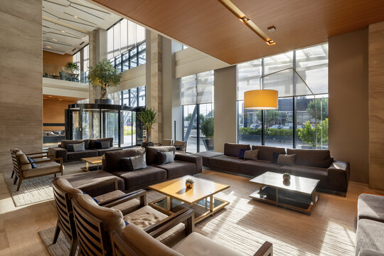 Spacious hotel lounge area with comfortable sofas wooden tables and large windows