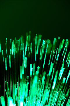 Futuristic abstract background featuring glowing green fiber optic light lines in close up view.