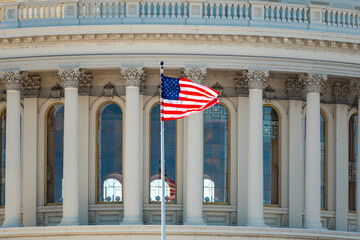 Naklejka premium Capitol with american flag near famous landmark. Us flag on capitol with columns. American flag near capitol as national symbol. Capitol with american flag.