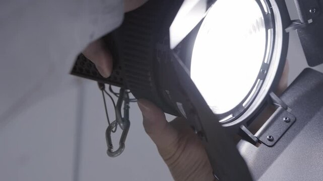 Extreme Close up of Gaffer Hands Adjusting Fresnel Studio Light for Video Production
