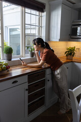 Smartphone resting on wooden countertop undercabinet lighting with bowl of apples at window © wavebreak3