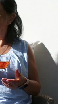 Vertical video: After off-frame voice, woman in blue top sipping tea in teacup at home, copy space