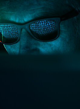 Cyber Crime, reflection in spectacles of virus hacking a computer, close up of face