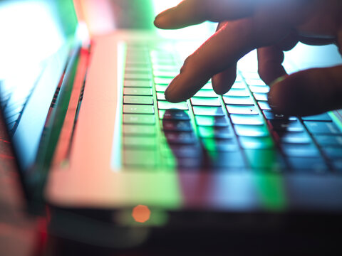 Hands typing on laptop keyboard in dark at home office