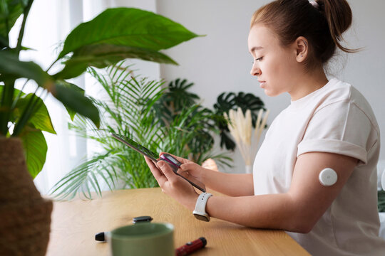 Woman with diabetes synchronizing tablet PC and glucometer on table at home