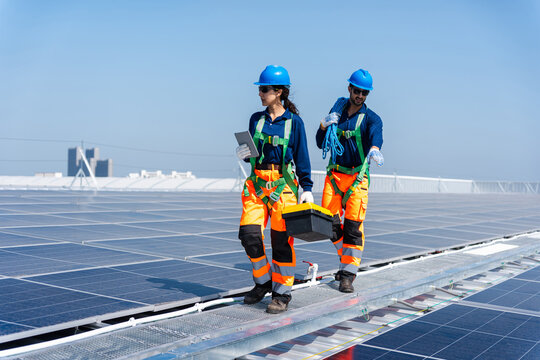 Team of workers installing solar panels on rooftop, Solar energy technicians inspecting photovoltaic modules on industrial roof, Professional team maintaining solar panel system for sustainable