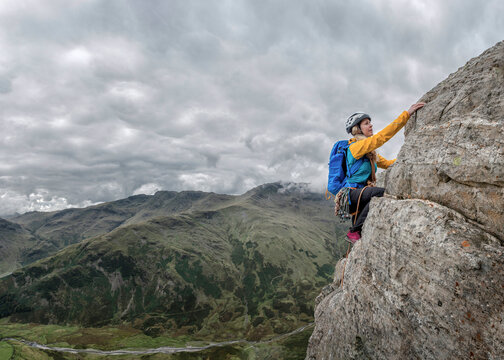 UK, Lake District, Great Langdale, woman scrambling at Pike of Stickle