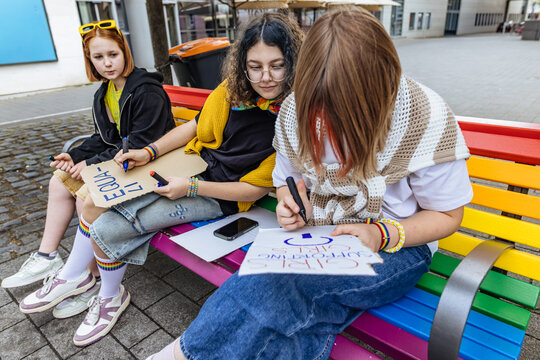 Activist making a sign for a pride parade outdoors on a bench