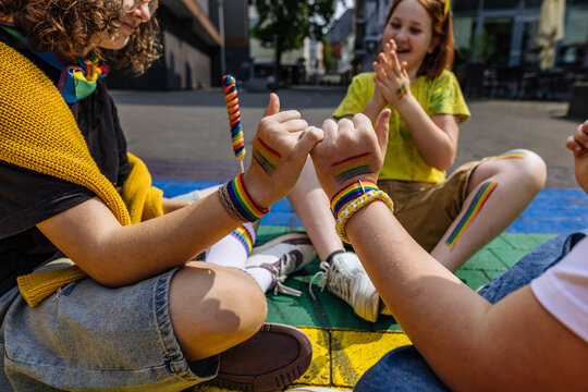 Friends making pinky promise at outdoor pride parade