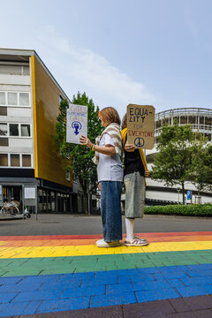 Activist holding equality sign outdoors on rainbow crosswalk