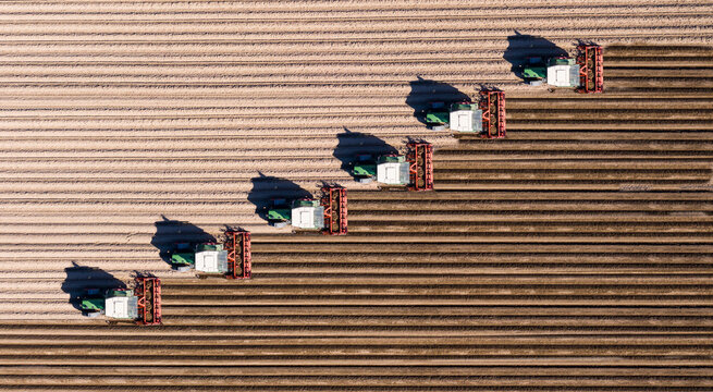 Germany, Hesse, Bergstarsse, Aerial view of tractors plowing brown field in spring