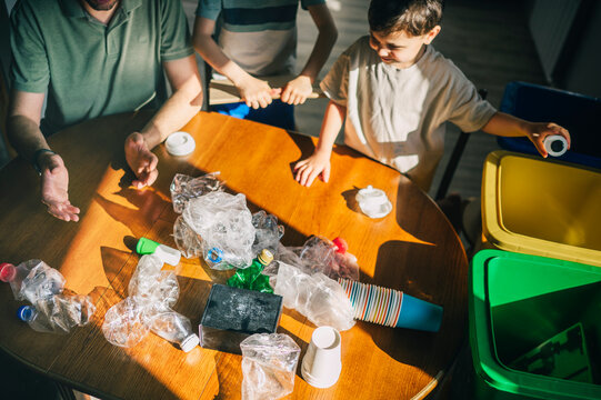 Father and child sorting plastic waste for recycling indoors