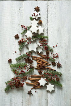 Star shaped cookies, cinnamon sticks, fir twigs, star anise, cookie cutters, pine cones and rose hips arranged into shape of Christmas tree