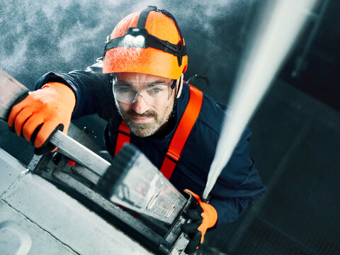 Industrial worker wearing hard hat and climbing harness ascending ladder