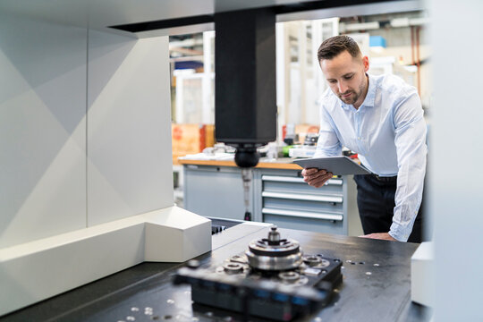 Businessman using tablet at a machine in a modern factory