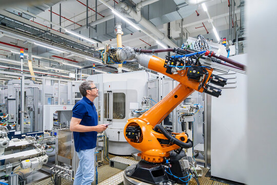 Engineer inspecting industrial robot arm in modern factory