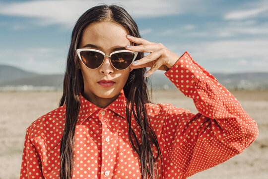 Woman wearing sunglasses in desert on sunny day