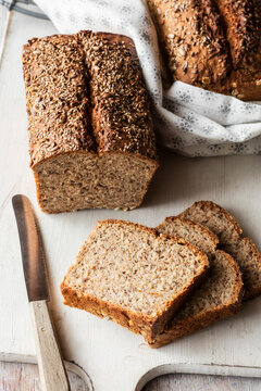 Loaf and slices of brown bread on cutting board