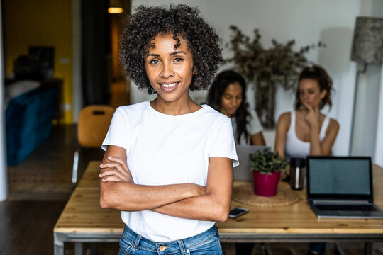 Portrait of smiling woman at home with friends in background