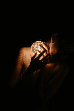 Hand holding a glowing light orb in the dark with deep shadows