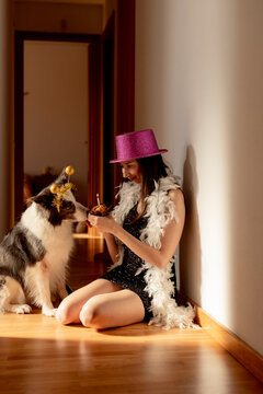 Woman sitting indoors celebrating her dogs birthday with a cupcake