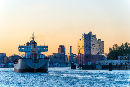 Cargo ship passing the Elbphilharmonie in Hamburg harbor at dawn