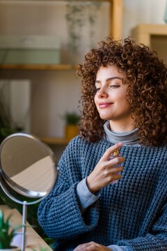 Woman spraying perfume at home for self-care and beauty