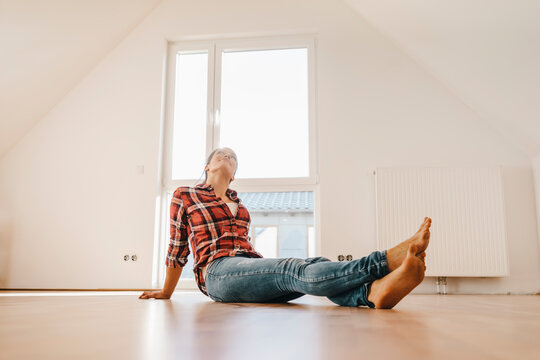 Mature woman moving house, sitting on floor, thinking