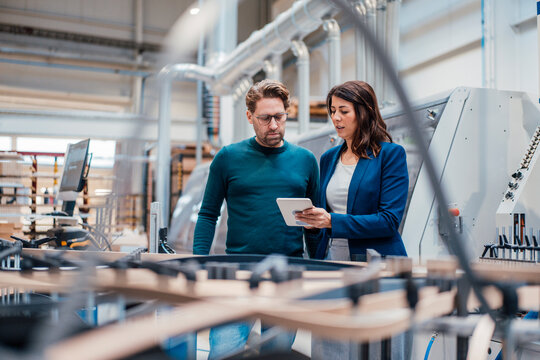 Engineers discussing over tablet computer in industry