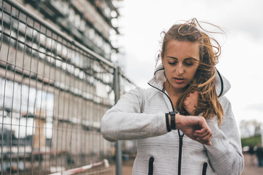 Sportive young woman outdoors looking on watch