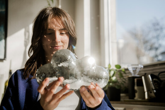 Young woman holding cloud shaped disco ball at home